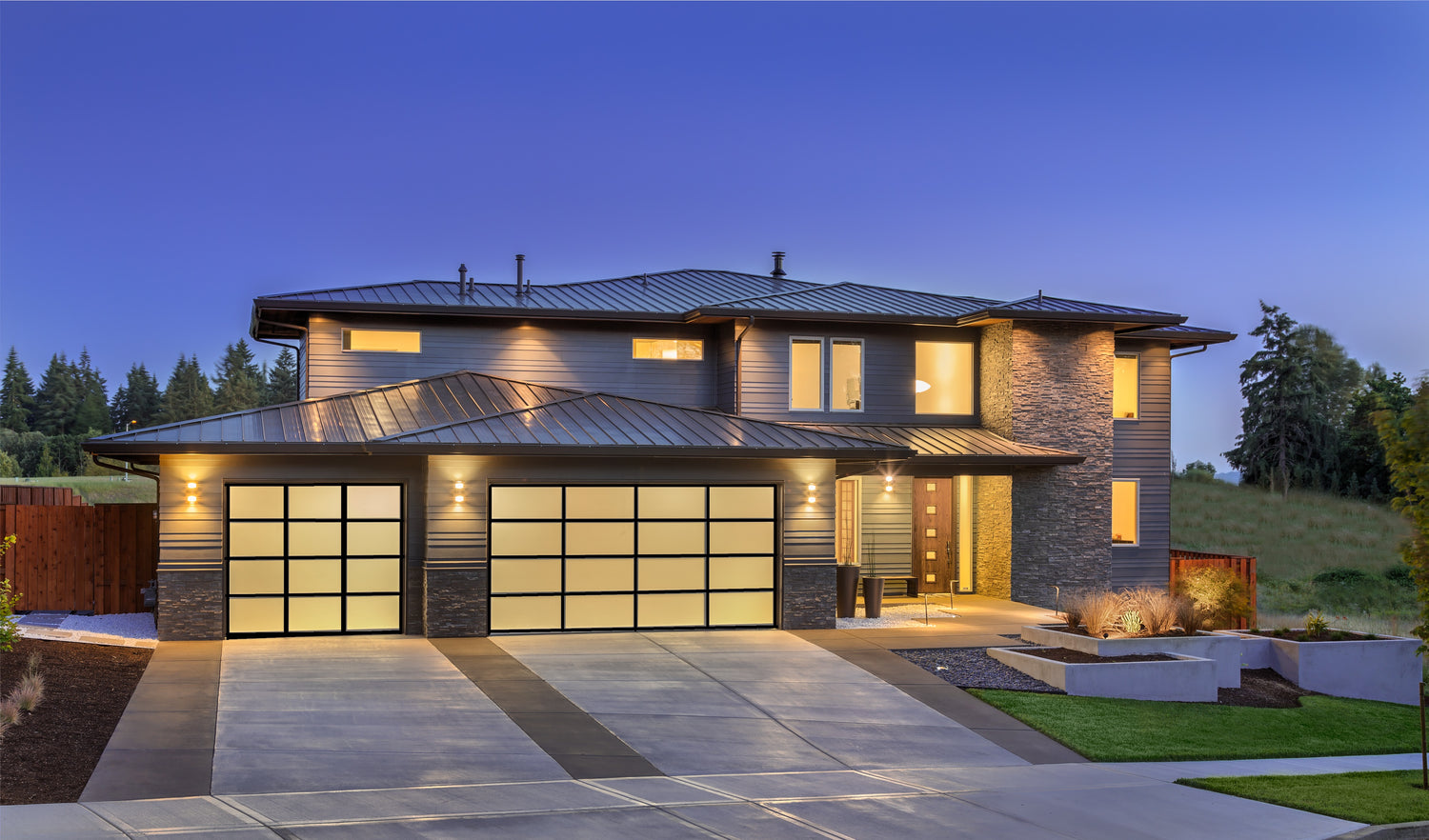 Modern home with frosted glass garage doors illuminated at dusk, showcasing a sleek and stylish exterior